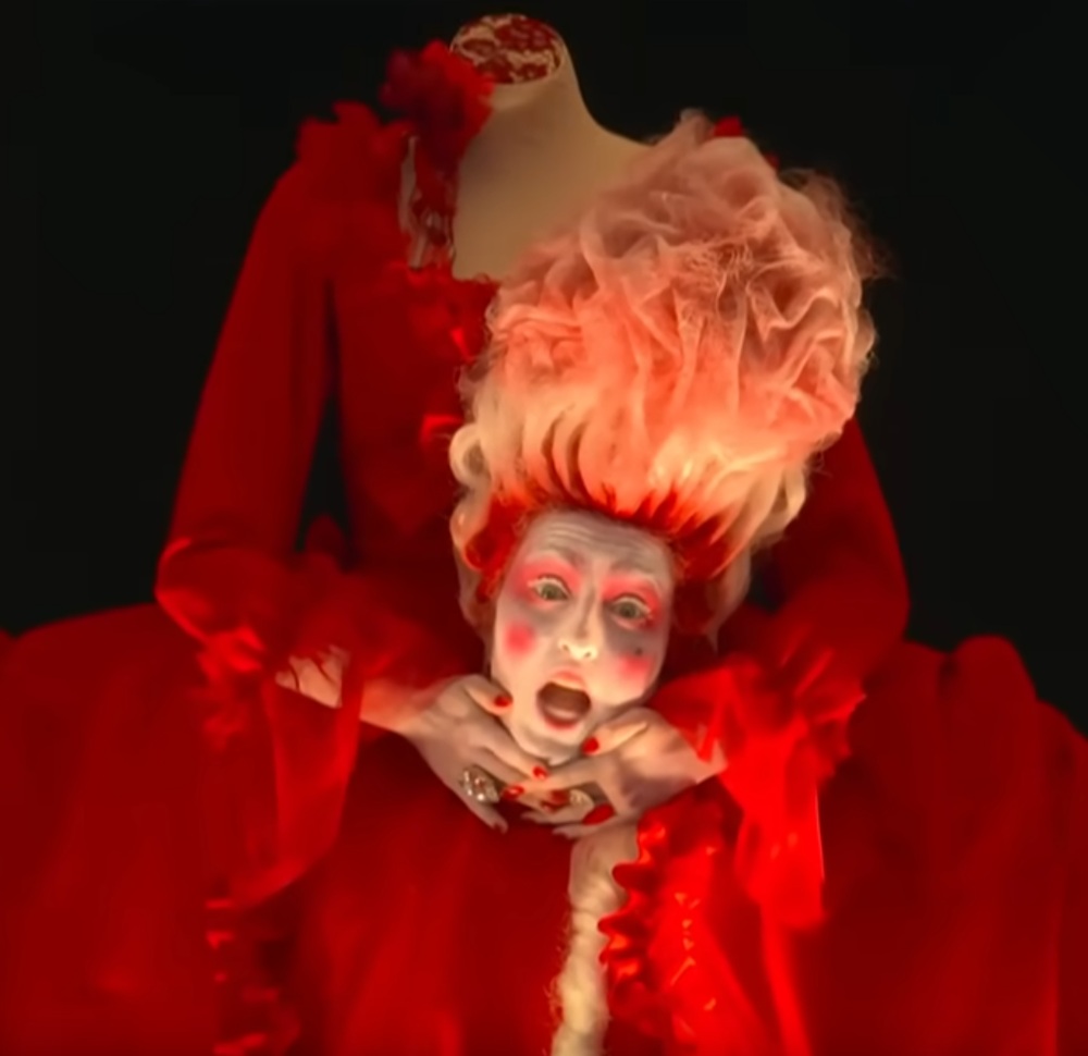 headless woman in a red dress holding her head and singing